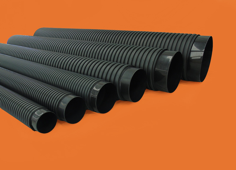 Fileiras de tubos Tucano Infraestrutura pretos com design corrugado, prontos para implementação em projetos de abastecimento e saneamento, sobre um fundo laranja vibrante.