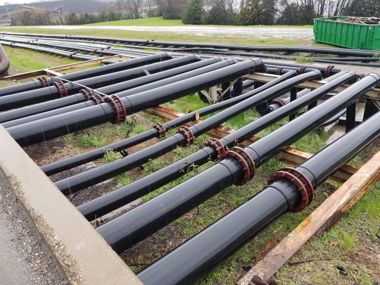 Tubulação Tucano Liso para infraestrutura, com tubos de Polietileno de Alta Densidade acoplados por flanges, organizados paralelamente sobre suportes metálicos, indicando uso em sistemas de abastecimento de água e saneamento.